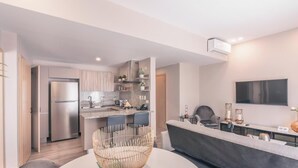 A modern kitchen with a built-in refrigerator, a dining area with a round table and chairs, and a living area with a sofa and a flat-screen TV. - Flat in Regatta Ii with breakfast included 204 (Santo Domingo)