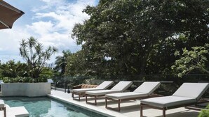 Una piscina con sillas de descanso y vistas a un paisaje urbano.