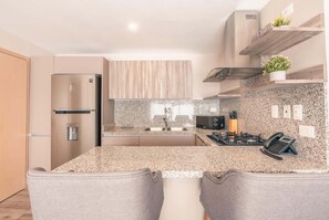A modern kitchen with a granite countertop, stainless steel appliances, and wooden cabinetry. - Regatta Living Ii with Breakfast Included! - 406 (Santo Domingo)
