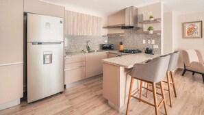 Eine moderne Küche mit einem Edelstahlkühlschrank, einem Gasherd und einer Arbeitsplatte aus Granit.