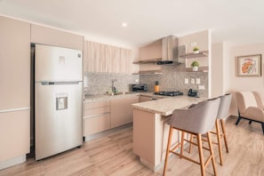 Eine moderne Küche mit einem Edelstahlkühlschrank, einem Gasherd und einer Arbeitsplatte aus Granit.