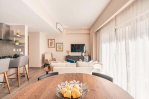 A modern living room with a wooden dining table, a sofa, and a TV in the background. - Regatta Living Ii with Breakfast Included! - 406 (Santo Domingo)