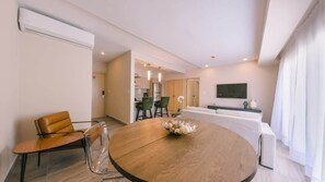 Ein modernes Wohnzimmer mit einem runden Holztisch, einer Couch und einem Fernseher.