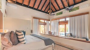 Ein Schlafzimmer mit Bett, Vorhängen, einem Fenster mit Blick und einem Deckenventilator.