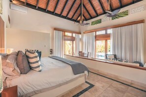 Ein Schlafzimmer mit Bett, Vorhängen, einem Fenster mit Blick und einem Deckenventilator.