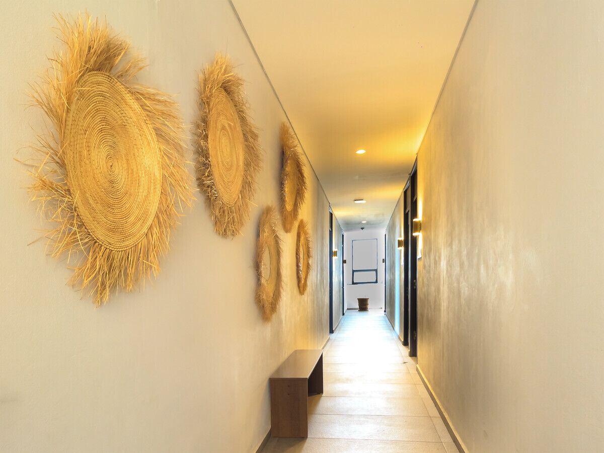 A hallway with a bench, decorative wall art, and a light fixture.