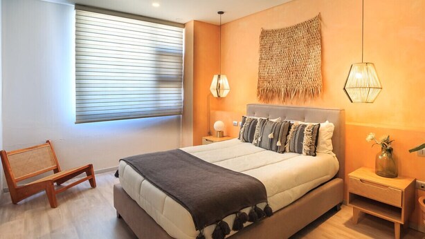 A modern bedroom with a large bed, a bedside table, a lamp, and a chair. - Private Suite with Incredible View & Pool (Guadalajara)