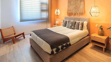 Een moderne slaapkamer met een groot bed, een nachtkastje, een lamp en een stoel.
