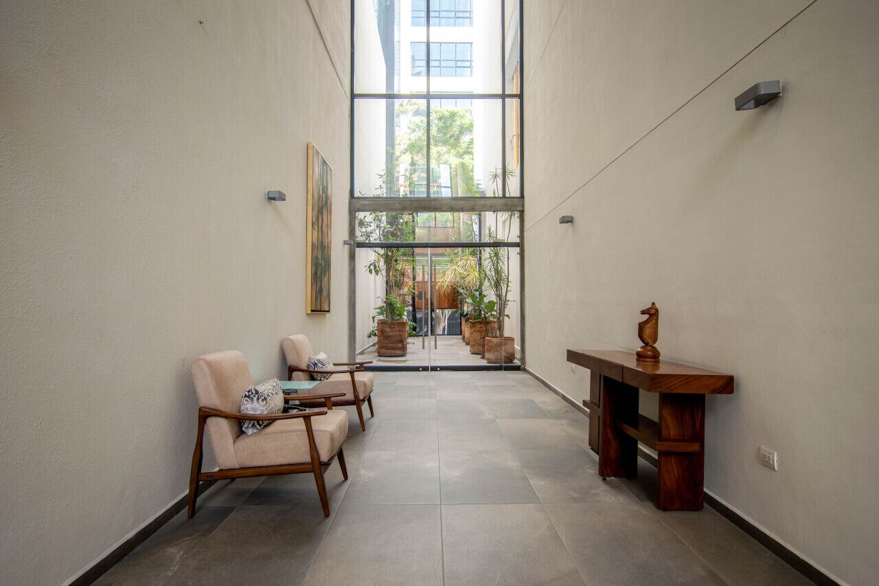 Un couloir avec un coin salon, une table en bois et une vue sur l’extérieur.