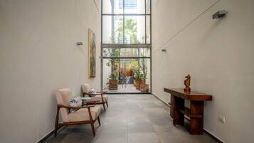 Un couloir avec un coin salon, une table en bois et une vue sur l’extérieur.