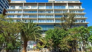 A multi-story hotel with a modern design, featuring a central courtyard with palm trees and potted plants. - Private Suite with Incredible View & Pool (Guadalajara)