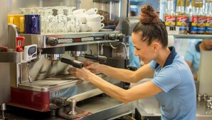 En person som använder en professionell espressomaskin i ett kök.