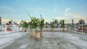 A rooftop terrace with potted plants, a city skyline in the background, and a white railing. - Modern King Studio in Central Roma Norte (Ciudad de México)