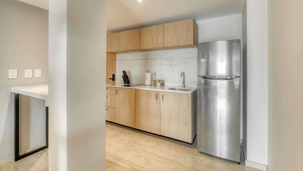 A modern kitchen with wooden cabinets, a stainless steel refrigerator, and a white countertop. - Modern King Studio in Central Roma Norte (Ciudad de México)