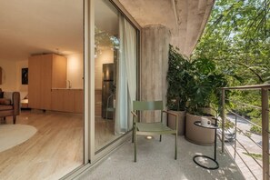 A modern living area with a glass door leading to a kitchen, a green chair, and a small table with a cup. - Modern Loft with Balcony & View of Parque Mexico (Ciudad de México)