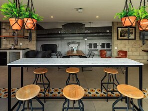 A bar area with a marble countertop, black metal stools, and hanging terracotta planters. - Double Deluxe Apartment with Terrace - 412 (Guadalajara)