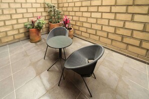 Eine Terrasse mit zwei Stühlen und einem Tisch, umgeben von Blumentöpfen.