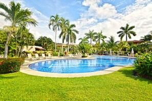 A swimming pool surrounded by palm trees and lounge chairs. - Bay Residence 7C -  3 bdr 2 bath (Playa Herradura)