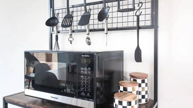 A kitchen with a microwave, checkered spice containers, and hanging utensils. - Shared Room Men / Low bed (Ciudad de México)