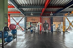 A gym with exercise equipment, a mural, and a view of the city. - Shared Room Men / Low bed (Ciudad de México)