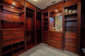 Ein begehbarer Kleiderschrank mit mehreren Schubladen und Regalen, einem Spiegel und einem kleinen Tisch mit Dekoration.