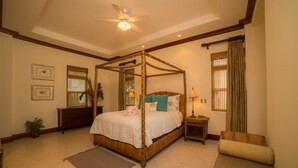 A four-poster bed with a canopy, a bedside table with a lamp, a chair, and a small table with a lamp. - Bella Vista 2D 3 bdr 3 1 and half bath (Playa Herradura)