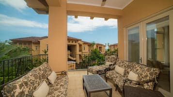 Un balcon aménagé avec un ensemble de canapés, une table et une vue sur les immeubles voisins.