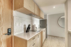 A modern kitchen with wooden cabinets, a countertop, a sink, and a refrigerator. - Modern King Studio in Central Roma Norte (Ciudad de México)