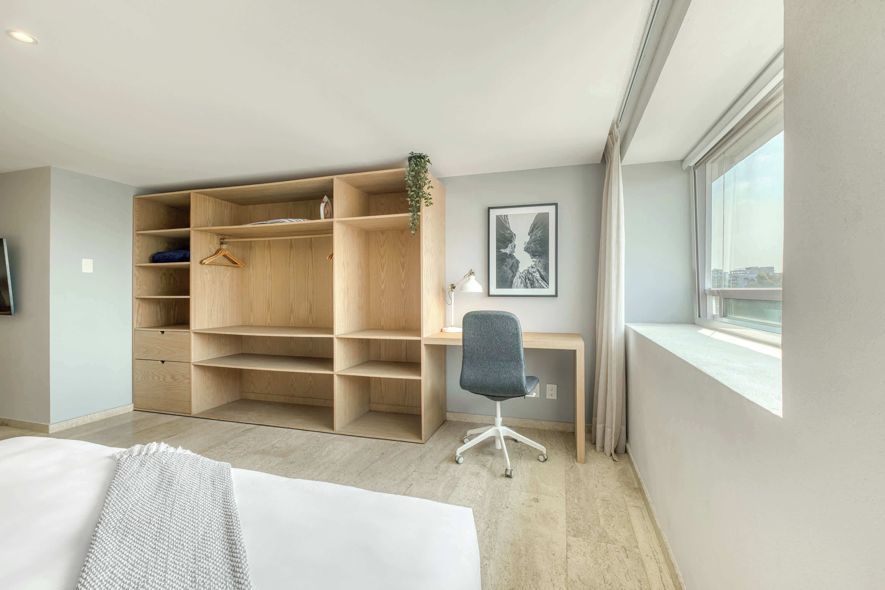A modern bedroom with a large wooden wardrobe, a desk, and a chair.