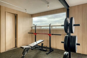 A gym with a bench press, squat rack, and weight plates. - Modern King Studio in Central Roma Norte (Ciudad de México)