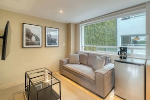 A modern living room with a sofa, a coffee maker, and framed pictures on the wall. - Modern King Studio in Central Roma Norte (Ciudad de México)