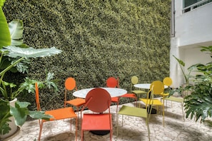 A patio area with round tables and chairs, surrounded by a lush green wall. - Modern King Studio in Central Roma Norte (Ciudad de México)