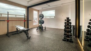 A gym with weightlifting equipment, a bench, and large windows. - Modern King Studio in Central Roma Norte (Ciudad de México)