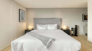 A modern hotel room with a large bed, two bedside tables with lamps, a heater, and a chair. - Modern King Studio in Central Roma Norte (Ciudad de México)