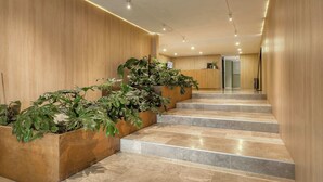 A modern hotel lobby with a wooden wall, a reception desk, and a staircase with potted plants. - Modern King Studio in Central Roma Norte (Ciudad de México)