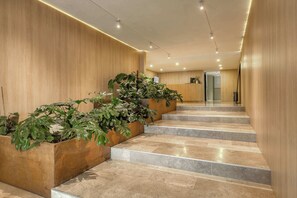 Eine moderne Hotelhalle mit einer Holzverkleidung, einem Empfangsbereich und einer Treppe mit Blumentöpfen.