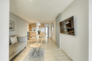 Ein modernes Wohnzimmer mit einer Couch, einem kleinen runden Tisch und einem an der Wand befestigten Fernseher.