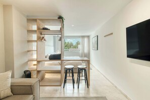 Una camera moderna con un letto, una TV, una scrivania con due sgabelli e una finestra vista.