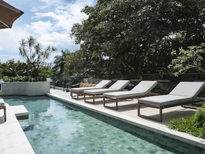 Una piscina con sillas de descanso y vistas a un paisaje urbano.