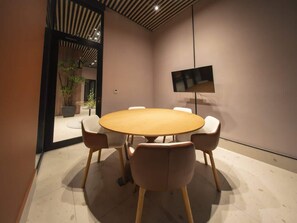 A conference room with a round table, four chairs, a flat-screen TV, and a potted plant. - Loft-Style 1br Apt At coco del mar (Panamá)