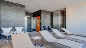 Ein moderner Wellnessbereich mit Liegestühlen, einer Rezeption und einer Glastrennwand.