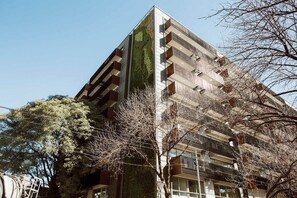 En bygning i flere etager med et moderne arkitektonisk design, der kombinerer altaner og store vinduer.
