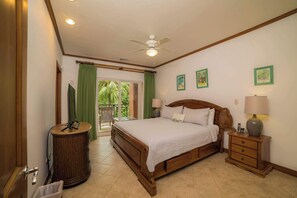 Un dormitorio con cama, mesita de noche, lámpara y vistas al exterior.
