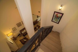 Una escalera con barandilla de madera que lleva a un espacio de estar con sofá y lámpara.