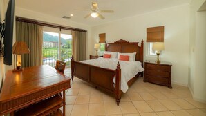 A bedroom with a bed, a desk, a chair, a nightstand, a lamp, a ceiling fan, and a window with curtains. - Del Mar 4G - 3 bdr 2 bath (Playa Herradura)
