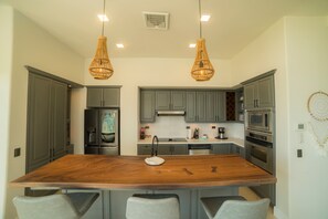 A modern kitchen with grey cabinets, a wooden island, and two hanging wicker pendant lights.