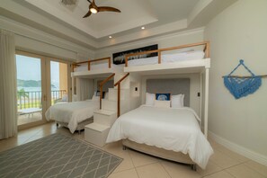 A hotel room with two beds, a balcony, and a view of the sea.