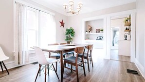 A dining area with a wooden table and chairs, a chandelier, and a red star decoration on the wall. - Olde Town Ambler A Distinctive Walkable Retreat (Arvada)