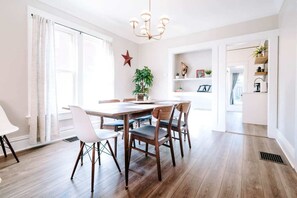A dining area with a wooden table and chairs, a chandelier, and a red star decoration on the wall. - Olde Town Ambler A Distinctive Walkable Retreat (Arvada)