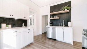 A modern kitchen with white cabinetry, a herringbone-patterned backsplash, and a wooden floor. - Olde Town Ambler A Distinctive Walkable Retreat (Arvada)